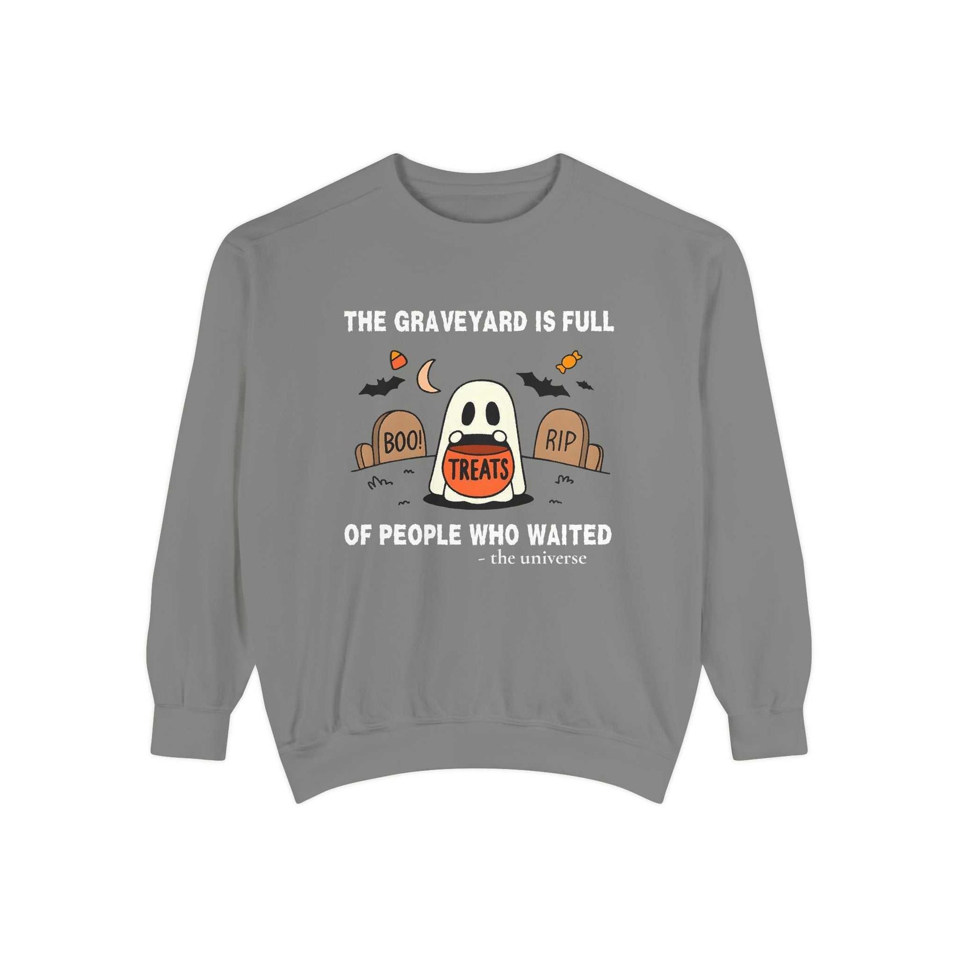 Sweatshirt with a ghost in a graveyard holding treats and Halloween text.