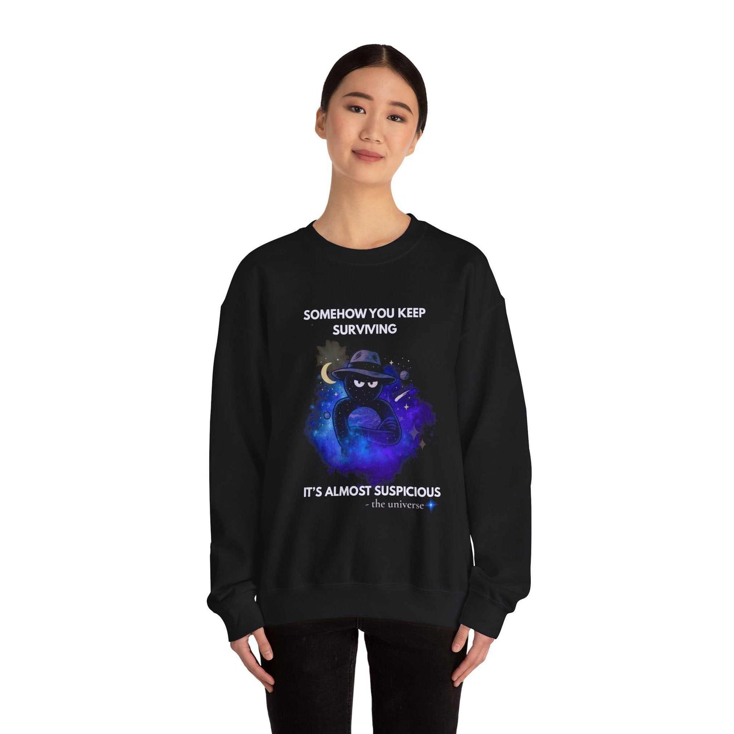 Black sweatshirt with a cosmic graphic and text that reads "Somehow you keep surviving. It's almost suspicious - the universe."