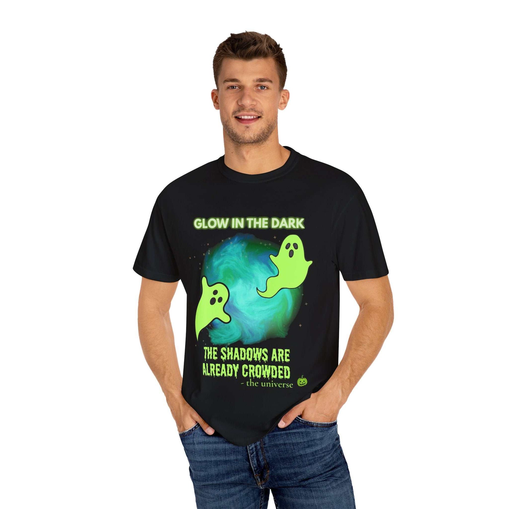 A man wears a black t-shirt with a glow-in-the-dark ghost design and text.