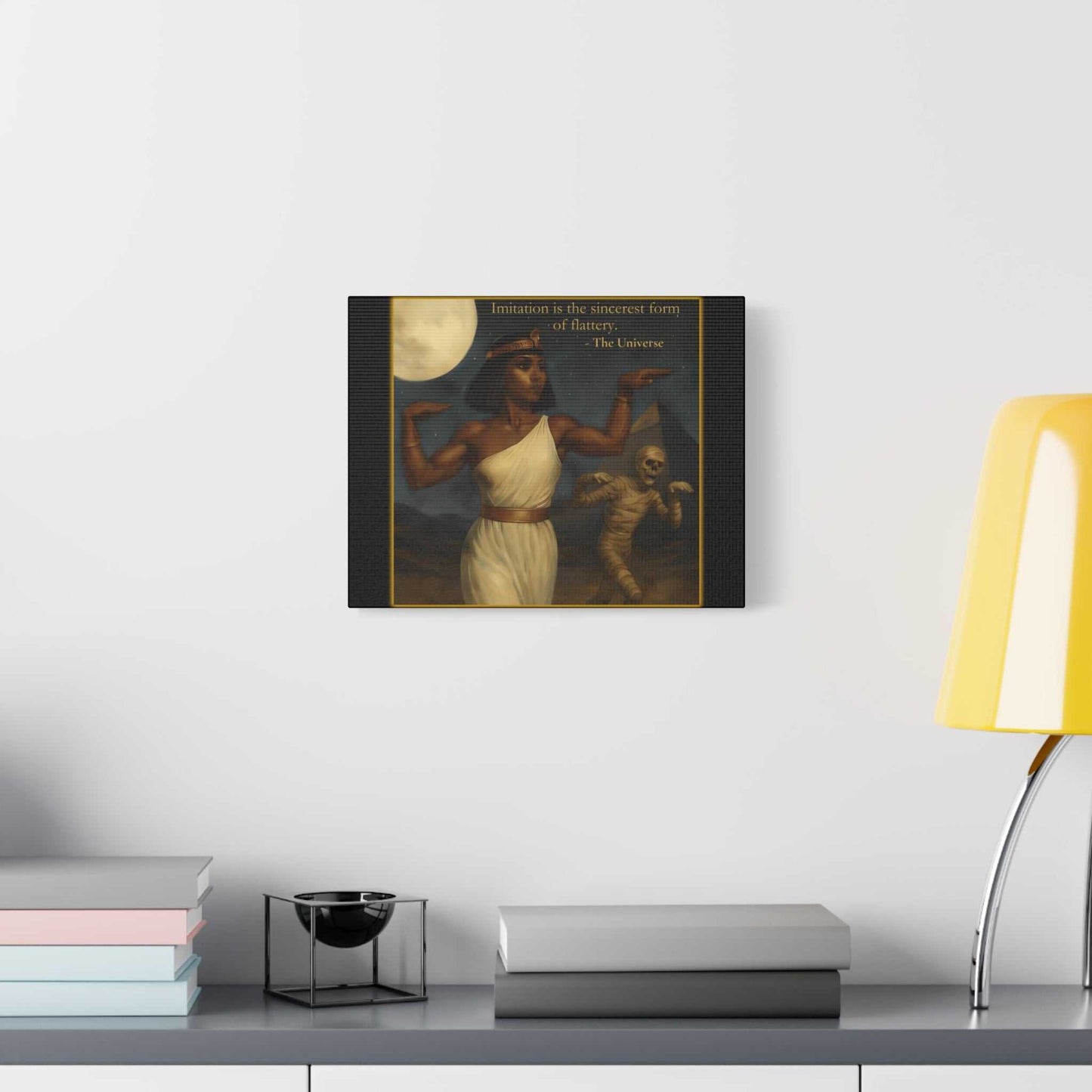 Modern wall art with Egyptian woman and mummy under moon, displayed above minimalist desk