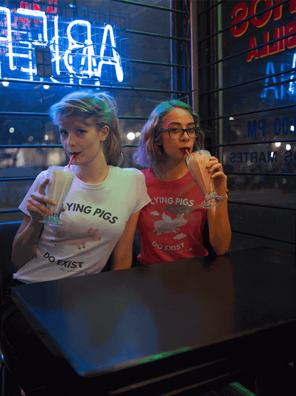 A white t-shirt with a graphic of a flying pig and the text "LYING PIGS DO EXIST".