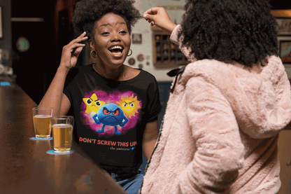 A black t-shirt with a graphic of three angry celestial characters and the text "DON'T SCREW THIS UP".