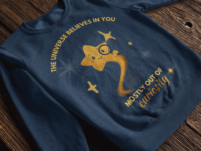 A navy blue sweatshirt with a graphic of a smiling star and the text "The Universe Believes in You Mostly Out of Curiosity".