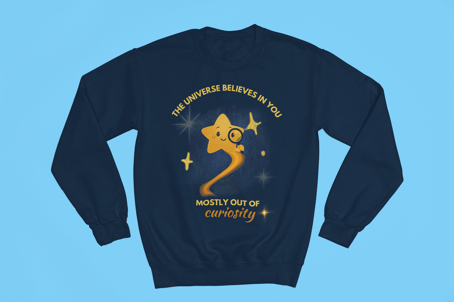 A navy sweatshirt with a graphic of a star looking through a magnifying glass and text that reads "The Universe Believes in You, Mostly Out of Curiosity".