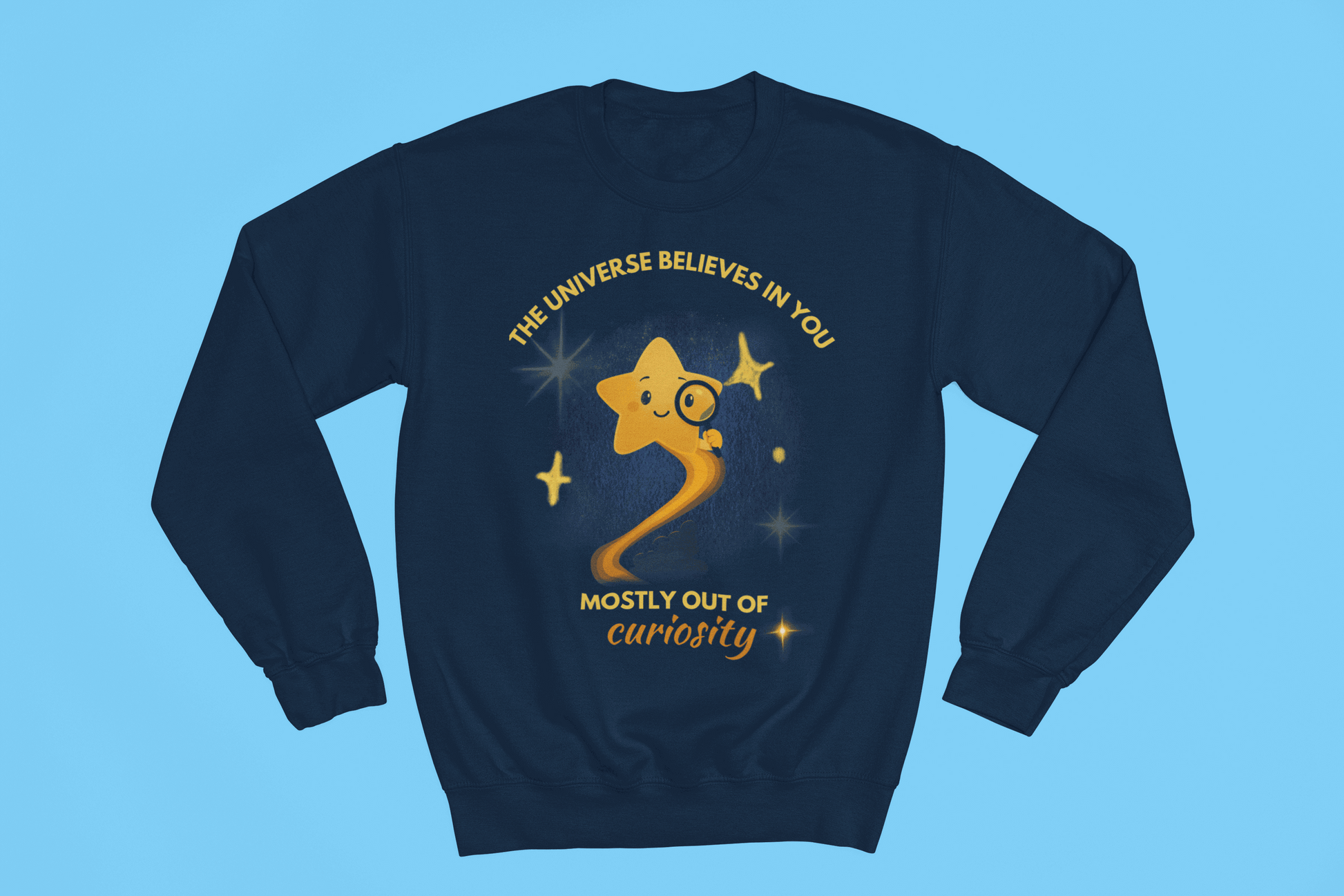 A navy sweatshirt with a graphic of a star looking through a magnifying glass and text that reads "The Universe Believes in You, Mostly Out of Curiosity".