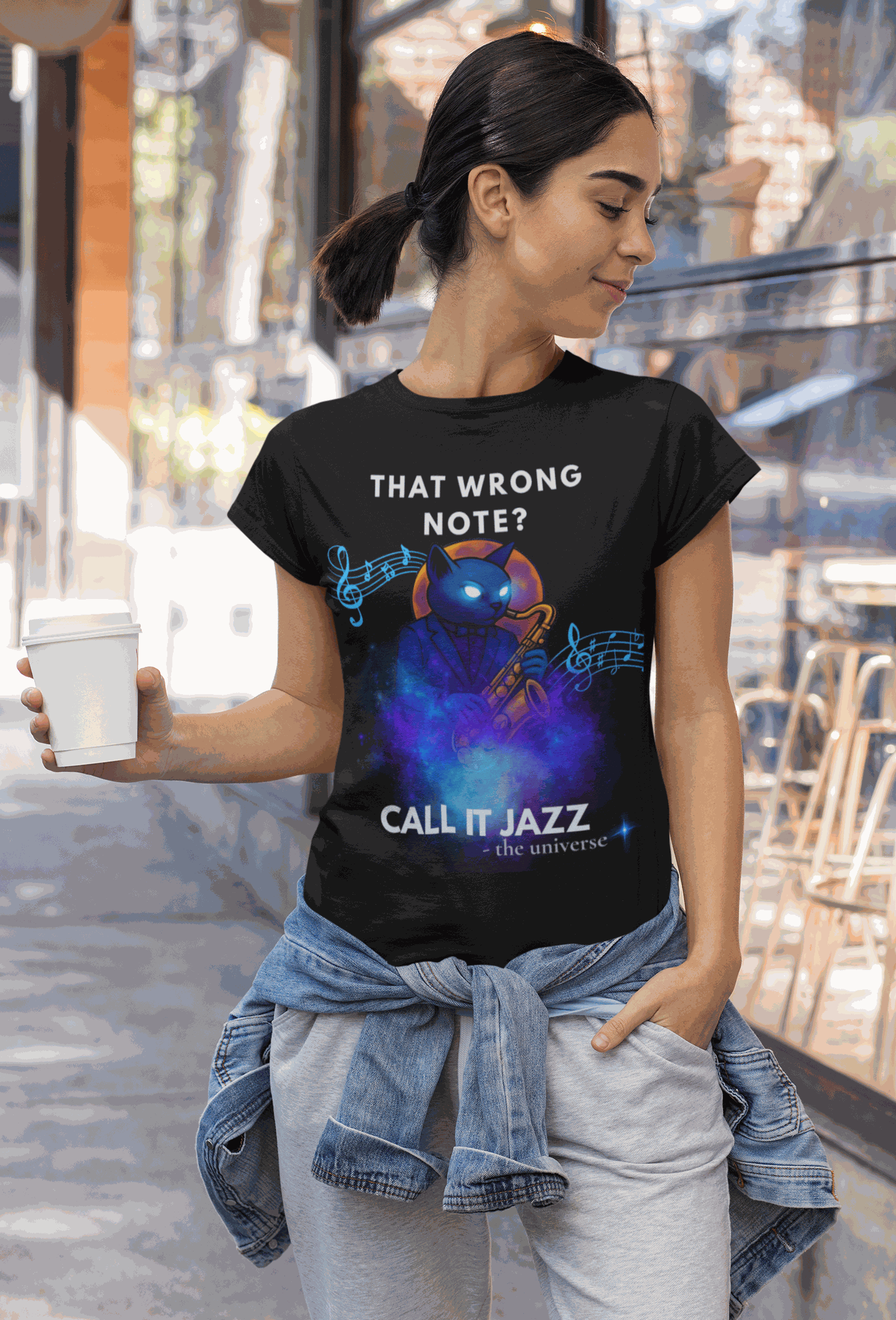 A woman wears a black t-shirt with a cosmic cat playing a saxophone and the text "That Wrong Note? Call It Jazz".