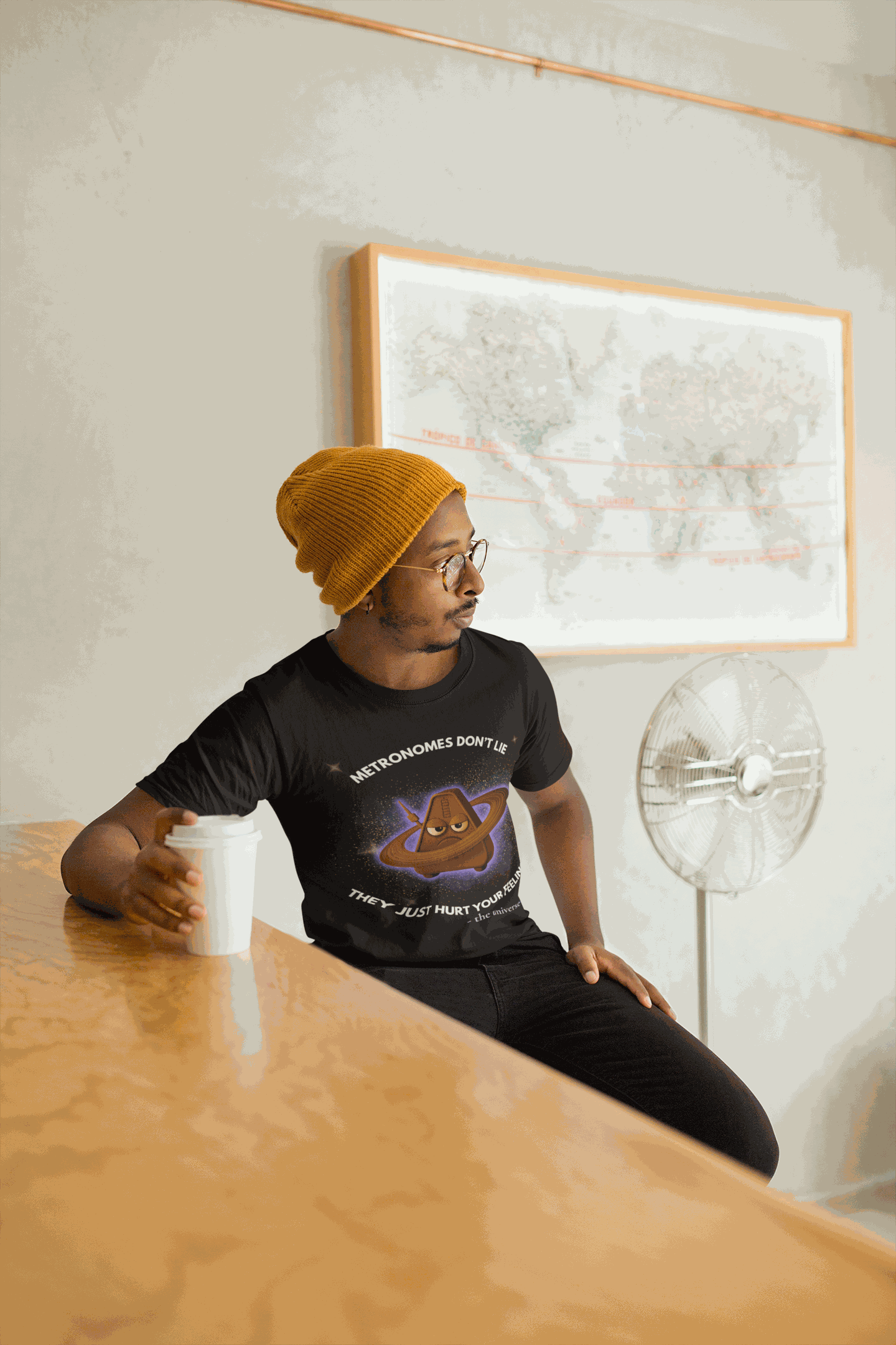 A man wears a black t-shirt with a graphic of an angry metronome in space.