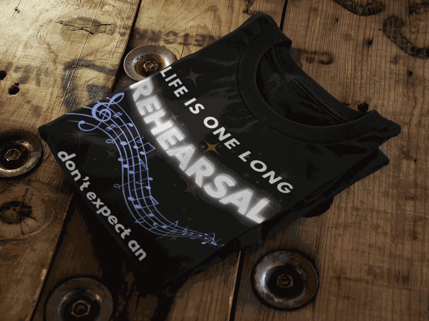 Black t-shirt with white text that reads "LIFE IS ONE LONG REHEARSAL don't expect an" and musical notes.