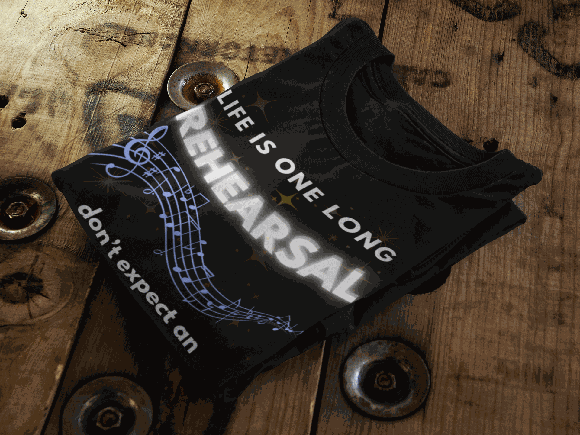Black t-shirt with white text that reads "LIFE IS ONE LONG REHEARSAL don't expect an" and musical notes.