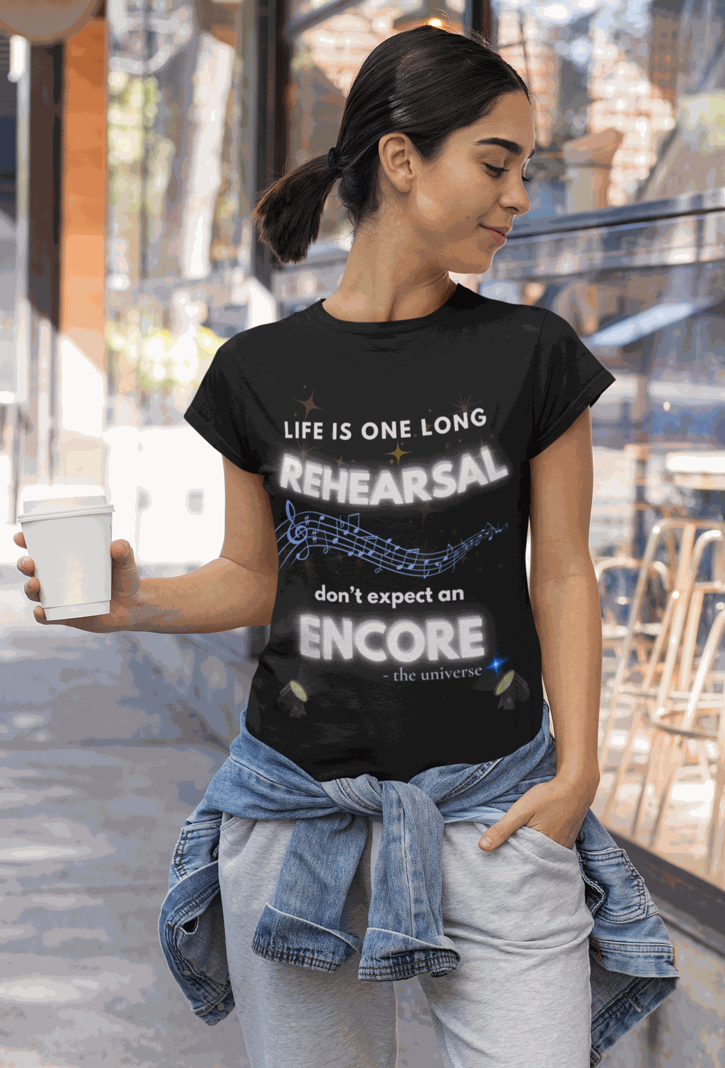 A woman wears a black t-shirt with the text "Life Is One Long Rehearsal, Don't Expect an Encore" and musical notes.