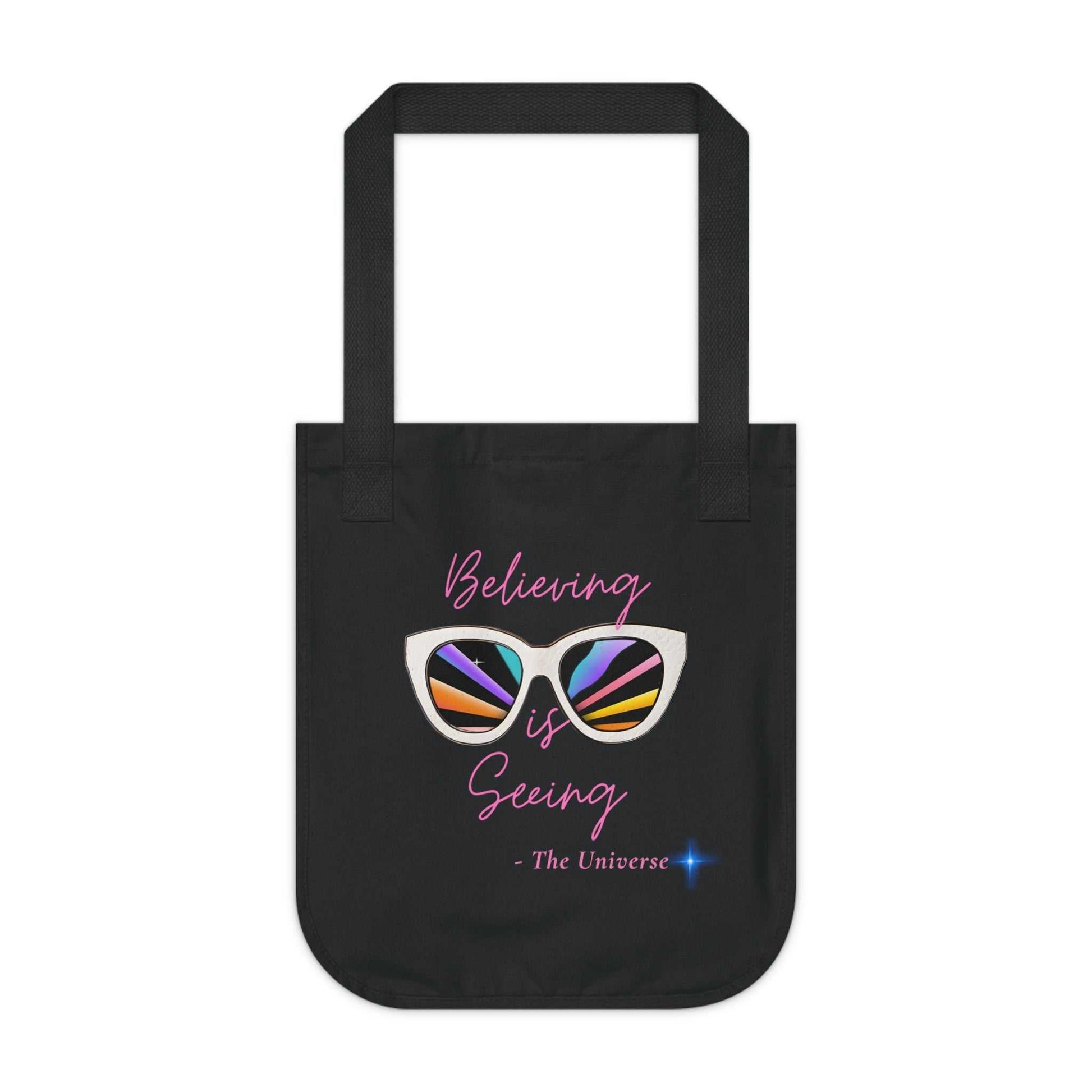 Black organic canvas tote bag with "Believing is Seeing" sunglasses graphic and long handles