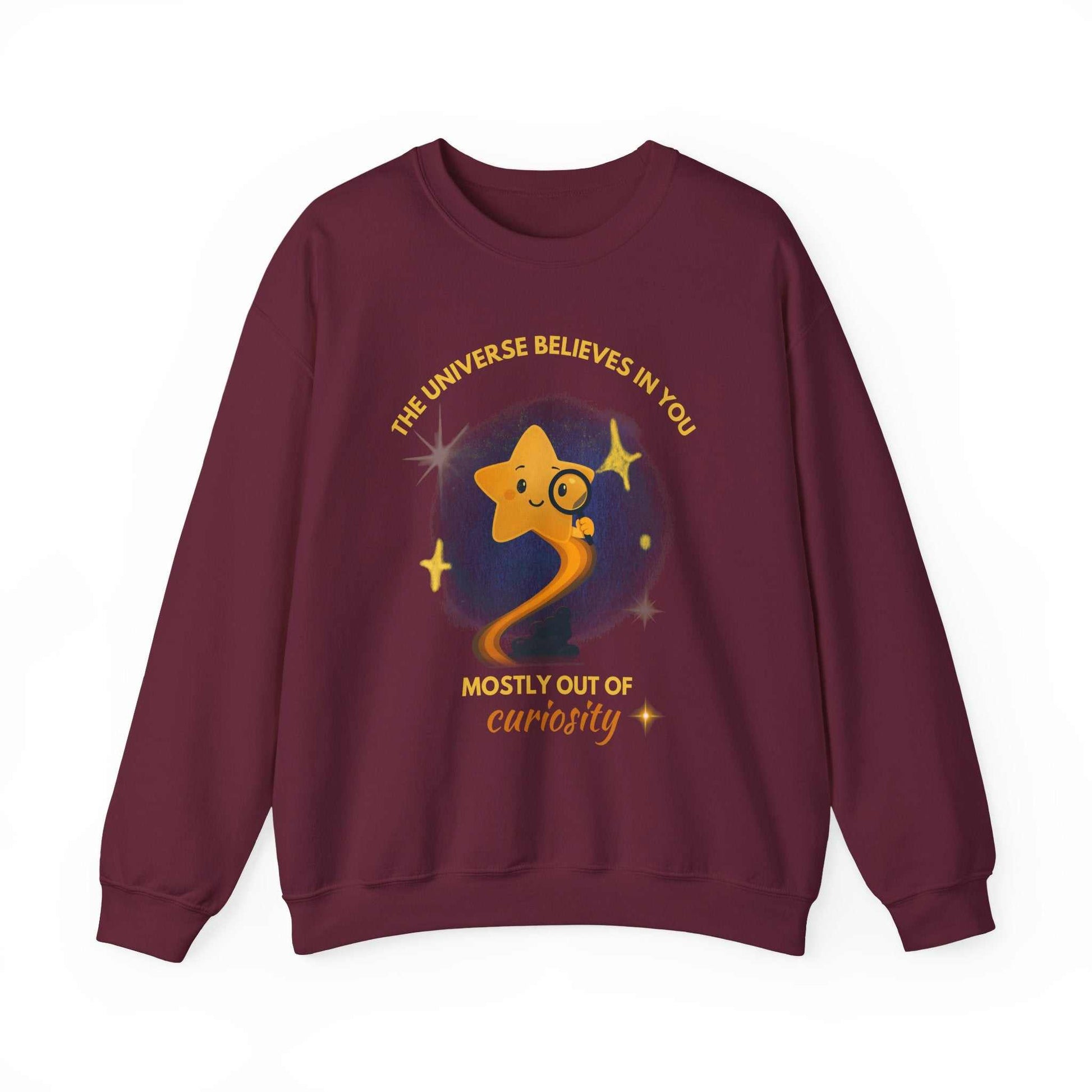 A maroon sweatshirt with a graphic of a star looking through a magnifying glass and text about curiosity.