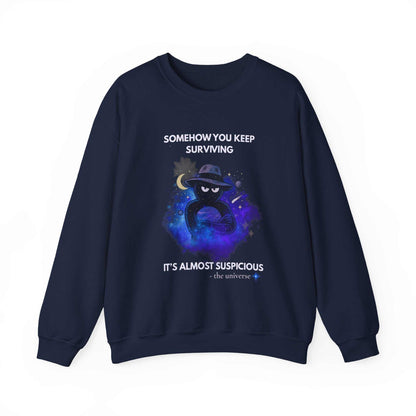 A navy sweatshirt with a cosmic graphic and the text "Somehow you keep surviving it's almost suspicious".